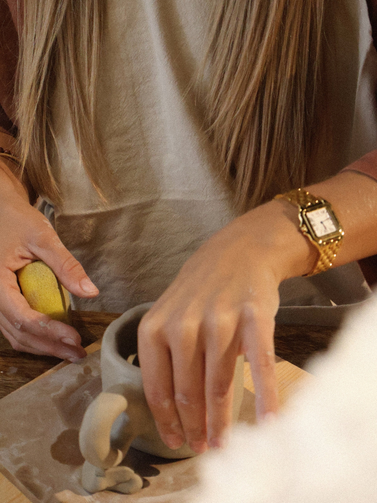 A participant smoothing the surface of a hand-built clay mug during a ceramic hand-building workshop in Dubai, in the calm creative atmosphere of Maison Terraē.