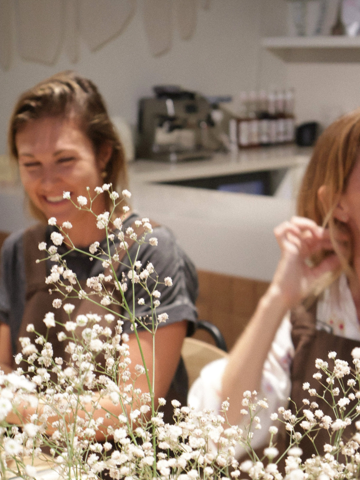 Friends enjoying a relaxed ceramic hand-building workshop in Dubai, with flowers creating a warm and inviting studio atmosphere, from Maison Terraē.