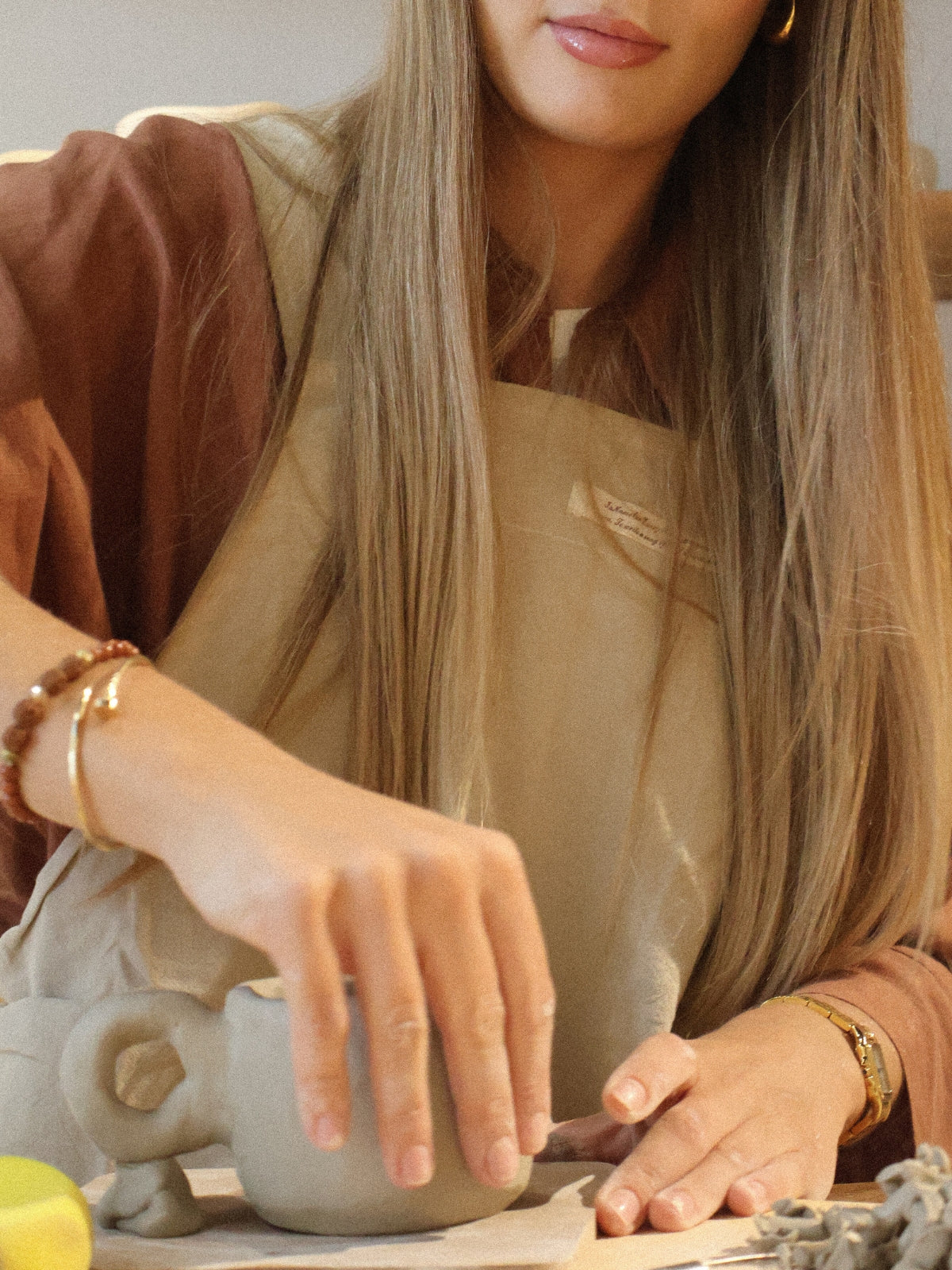 A participant shaping a clay piece by hand during a ceramic hand-building workshop in Dubai, in the calm and creative studio atmosphere of Maison Terraē.