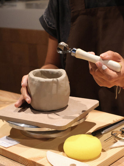 A participant carving details into a hand-built clay pot during a ceramic hand-building workshop in Dubai, using sculpting tools in the calm creative atmosphere of Maison Terraē.