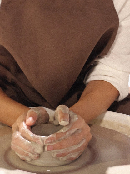 Hands shaping clay during a wheel-throwing ceramic class in Dubai from Maison Terraē.