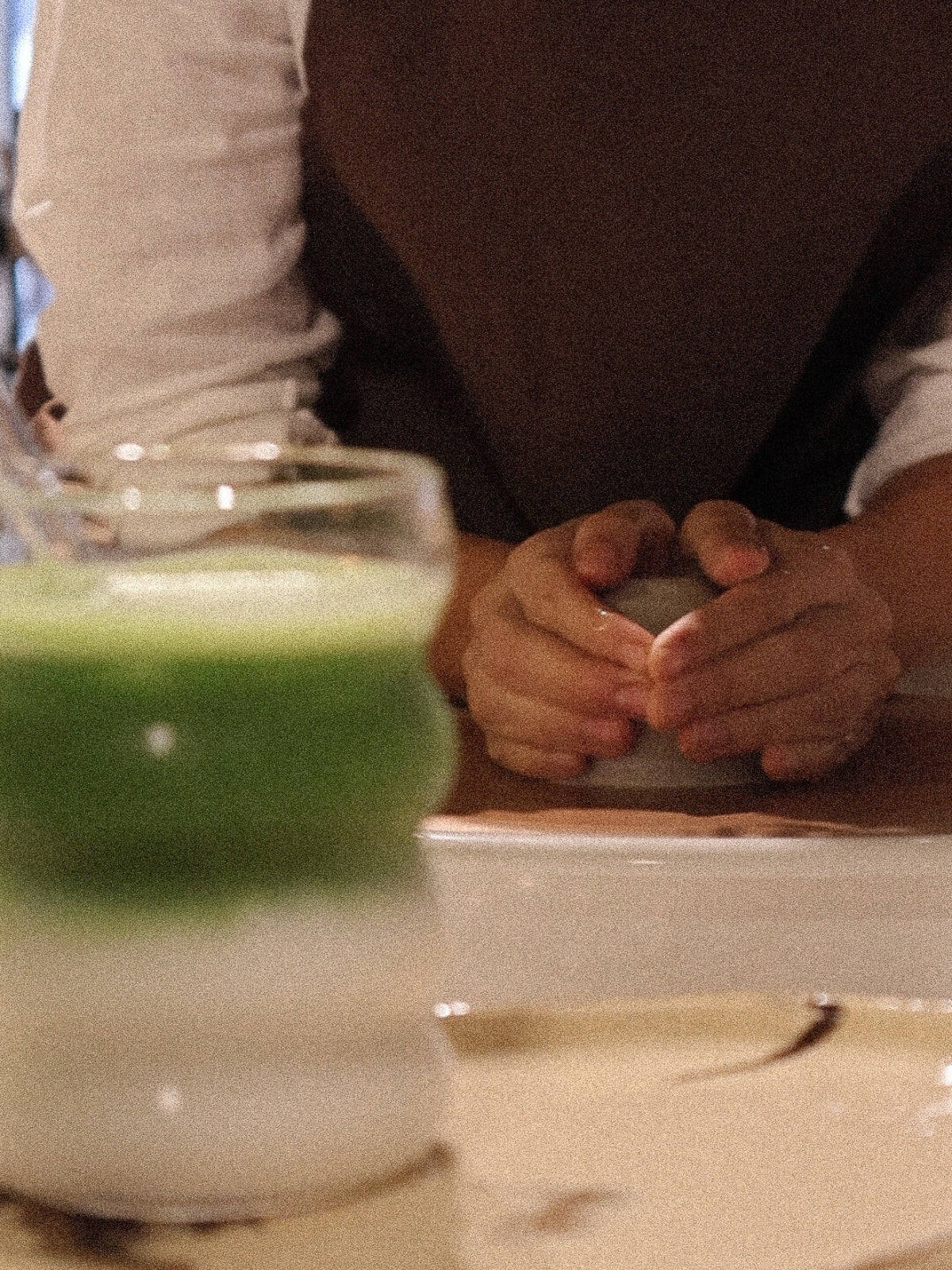A participant preparing clay during a ceramic workshop in Dubai, with a matcha latte in the foreground adding to the calm studio atmosphere, from Maison Terraē.